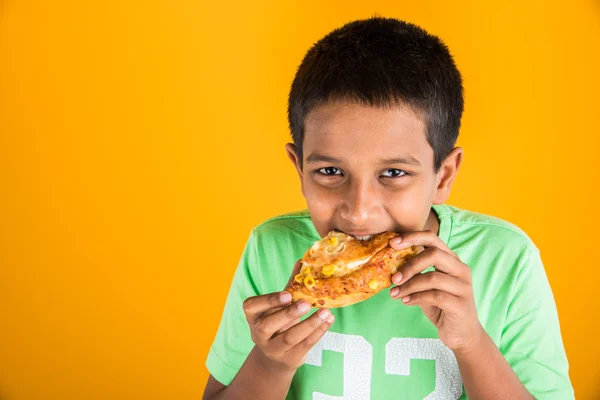 Indiase jongen eten pizza over gele achtergrond — Stockfoto