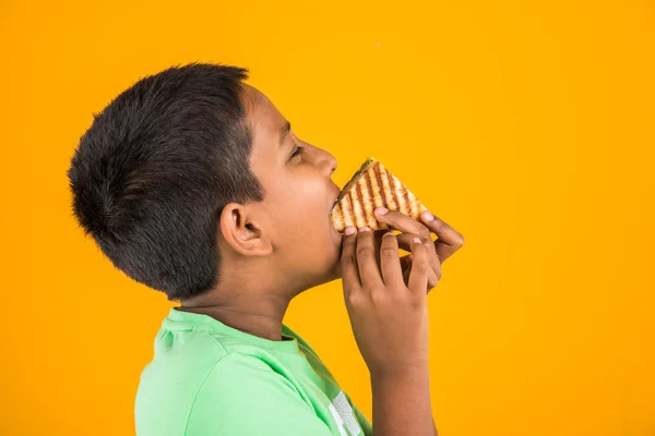 Indian Kid eten sandwich, Aziatische jongen en sandwich, Indische jongen tonen sandwich, schattige Afrikaanse jongen tonen sandwich op gele achtergrond — Stockfoto