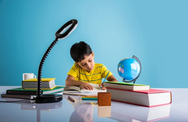 Indio pequeño niño estudiando o haciendo trabajo en casa, asiático chico estudiando con café taza, globo modelo y libros en mesa — Foto de Stock