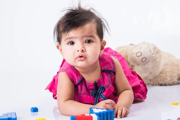 indian baby playing with toys or blocks, asian infant playing with toys on white background, indian baby girl playing with toys, indian toddler playing with toys, indian baby girl lying on white floor