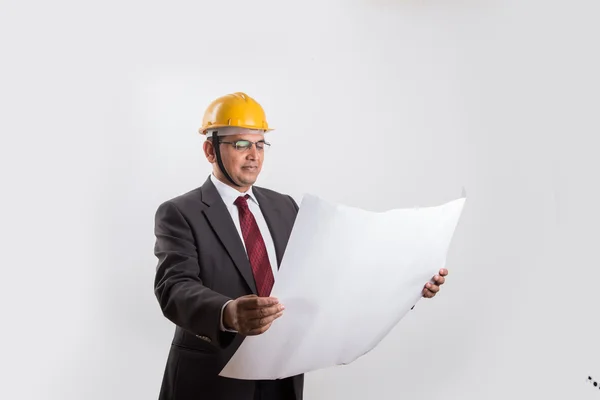 Ινδός επιχειρηματίας που κρατά ένα προσχέδιο, φορώντας κίτρινο σκληρό καπέλο, απομονωμένο σε λευκό φόντο — Φωτογραφία Αρχείου
