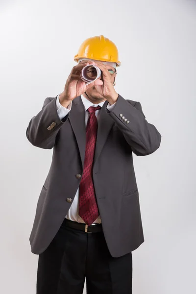 Indian businessman holding a blueprint, wearing yellow hard hat, isolated over white background — Stock Photo, Image