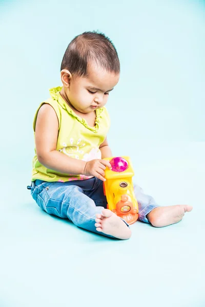 indian child playing with colourful toy. Isolated on blue background, indian girl playing with engine toy, asian girl playing with colourful toy engine