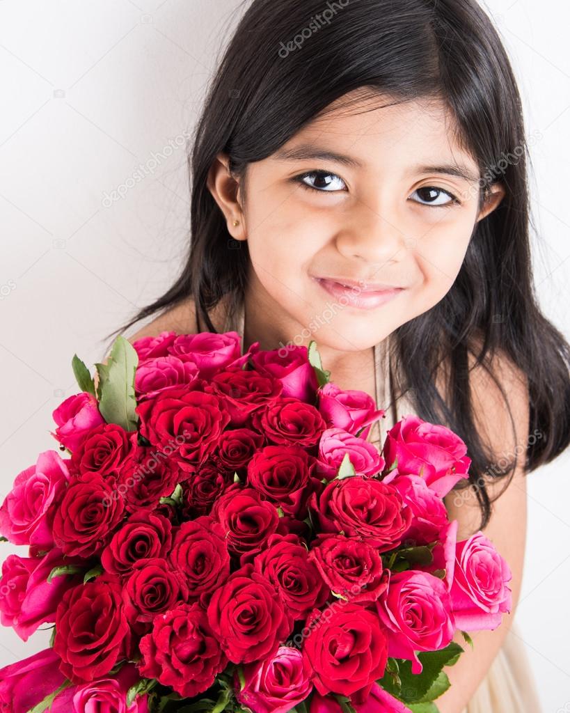 Indian little girl holding bouquet or red rose flowers, asian girl with
