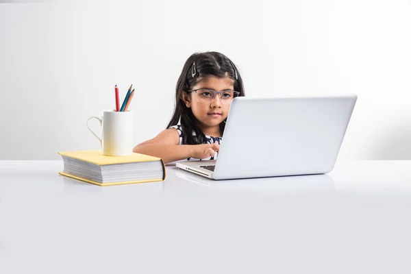 Alegre india niña utilizando el ordenador portátil, asiático niña pequeña jugando en el ordenador portátil, aislado sobre fondo blanco, linda niña india jugando en el ordenador portátil sobre la mesa de estudio — Foto de Stock