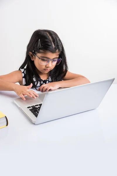 쾌활한 인도 어린 소녀 를 사용하여 노트북, 아시아 의 작은 소녀 재생 노트북, 고립 된 흰색 배경, 귀여운 인도 여자 재생 에 노트북 위에 연구 테이블 — 스톡 사진