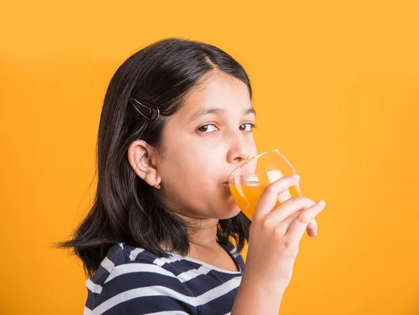 Portret van Indiase klein meisje het drinken van mango sap of vruchtensap in een glas, Aziatisch meisje en een glas sap, Indiase kleine meisje houden een glas mango sap of sinaasappelsap op gele achtergrond — Stockfoto