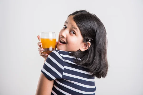 Indiase kleine meid het drinken van mango sap of vruchtensap in een glas, Aziatisch meisje en een glas sap, Indiase kleine meisje houden een glas mango sap of sinaasappelsap op witte achtergrond — Stockfoto