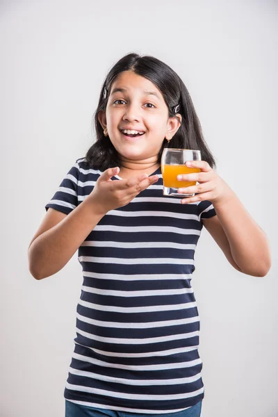 Portret van Indiase klein meisje het drinken van mango sap of vruchtensap in een glas, Aziatisch meisje en een glas sap, Indiase kleine meisje houden een glas mango sap of sinaasappelsap op witte achtergrond — Stockfoto