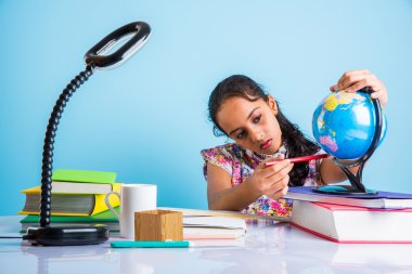 hintli kız öğrenci eğitim küre bakıyor ve kitap, masa lambası ve süt kupa ile masada oturan, asya kız çocuk coğrafya eğitimi, meraklı asya kız dünya ile coğrafya eğitimi