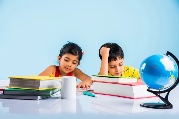 Indiase jongen en meisje studeren met globe op studielijst, Aziatische kinderen studeren, Indiase kinderen studeren geografie, kinderen doen van huiswerk of thuiswerk, twee kinderen studeren op tafel — Stockfoto