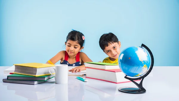 Indiase jongen en meisje studeren met globe op studielijst, Aziatische kinderen studeren, Indiase kinderen studeren geografie, kinderen doen van huiswerk of thuiswerk, twee kinderen studeren op tafel — Stockfoto