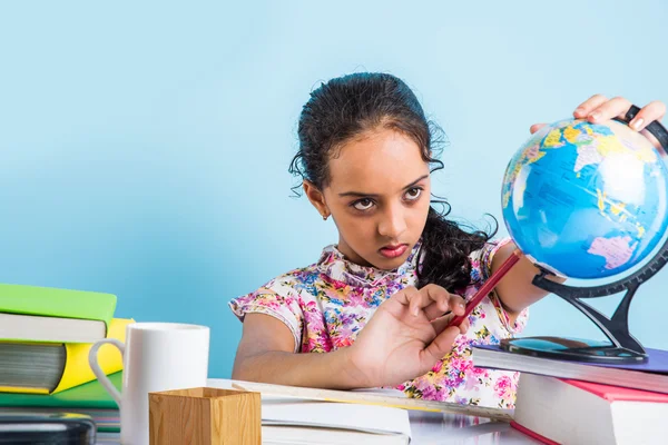 Indiase meisje student kijken naar educatieve Globe en zittend aan tafel met boeken, tafellamp en melk mok, Aziatische meisje kind studeren geografie, nieuwsgierig Aziatisch meisje studeren geografie met Globe — Stockfoto