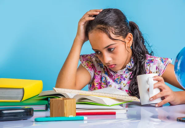 education and home concept - stressed student girl with books, indian girl child tired of studying or doing homework, asian girl studying and stressed, with globe toy and coffee mug