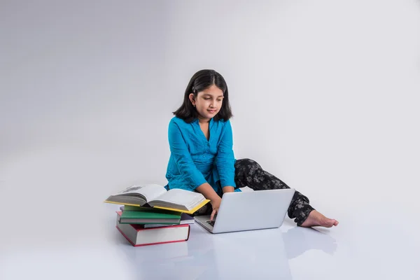 Linda niña india estudiando en el ordenador portátil, asiática niña pequeña estudiando y usando el ordenador portátil, inocente niña india niño y estudio concepto con pila de libros & portátil — Foto de Stock