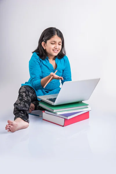 Cute little indian girl studying on laptop, asian small girl studying and using laptop, innocent indian girl child and study concept with pile of books & laptop — Stock Photo, Image