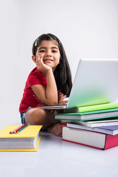 Linda niña india estudiando en el ordenador portátil, asiática niña pequeña estudiando y usando el ordenador portátil, inocente niña india niño y estudio concepto con pila de libros & portátil — Foto de Stock