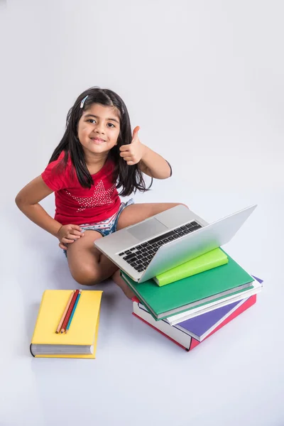 Мила маленька індійська дівчинка навчається на ноутбуці, азіатська маленька дівчинка вивчає та використовує ноутбук, невинна індійська дівчинка-дитина та вивчає концепцію з купою книг та ноутбуків — стокове фото