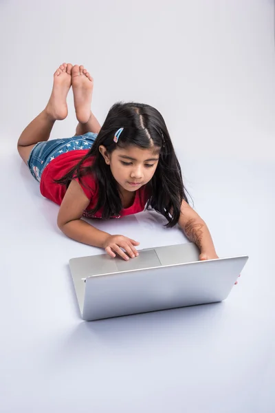 쾌활한 인도 어린 소녀 를 사용하여 노트북, 아시아 의 작은 소녀 재생 노트북, 고립 된 흰색 배경, 귀여운 인도 여자 거짓말 에 누워 바닥에 재생 에 노트북 — 스톡 사진