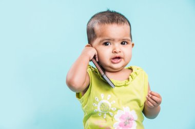 Cep telefonu mavi izole konuşmak kız mutlu bebek. Portre. Hint küçük kız ve hareket eden ya da cep telefonu, akıllı telefon kullanan Asya bebek kız