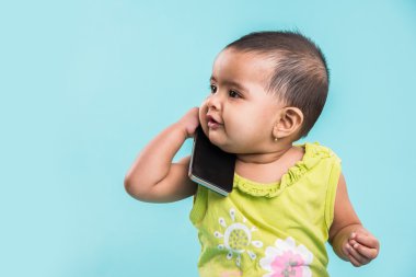Cep telefonu mavi izole konuşmak kız mutlu bebek. Portre. Hint küçük kız ve hareket eden ya da cep telefonu, akıllı telefon kullanan Asya bebek kız