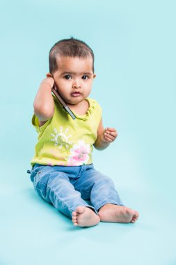 Cep telefonu mavi izole konuşmak kız mutlu bebek. Portre. Hint küçük kız ve hareket eden ya da cep telefonu, akıllı telefon kullanan Asya bebek kız