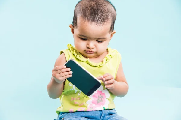 Happy baby girl talking on mobile phone isolated on blue. Closeup. Indian little girl and mobile or handset, asian baby girl using smartphone — Stock Photo, Image
