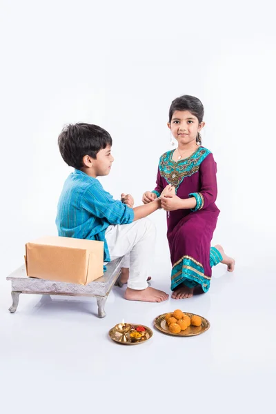 Cute indian Sister tying Rakhi on her brother's wrist on the occasion of Rakshabandhan 0r raksha bandhan or Rakhi festival, isolated on white background — Stock Photo, Image