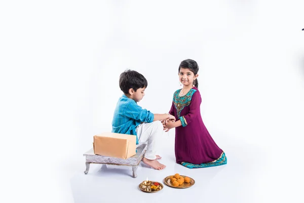 Χαριτωμένο Ινδικό αδελφή δέσιμο Rakhi στον καρπό του αδερφού της με την ευκαιρία του Rakshabahan 0r Rakhi Bandhan ή Rakhi φεστιβάλ, απομονώνονται σε λευκό φόντο — Φωτογραφία Αρχείου