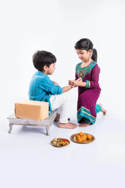 Linda hermana india atando Rakhi en la muñeca de su hermano con motivo de Rakshabandhan 0r raksha bandhan o festival Rakhi, aislado sobre fondo blanco — Foto de Stock