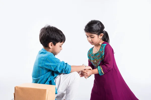 Linda hermana india atando Rakhi en la muñeca de su hermano con motivo de Rakshabandhan 0r raksha bandhan o festival Rakhi, aislado sobre fondo blanco — Foto de Stock