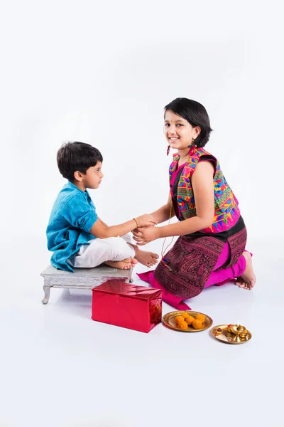 Schattige Indiase zuster koppelverkoop Rakhi op de pols van haar broer ter gelegenheid van Rakshabandhan 0r Raksha bandhan of Rakhi Festival, geïsoleerd op witte achtergrond — Stockfoto