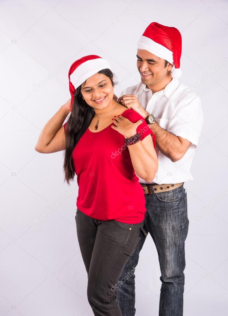 Man placing necklace on woman's neck in christmas time, indian man gifting necklace to wife of girlfriend on christmas, asian couple and gifting necklace, isolated on white background, standing pose