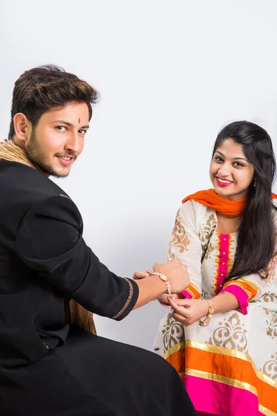 Indian sister applying tika on brother's forehead, enjoying and celebrating Raksha Bandhan festival — Stock Photo, Image