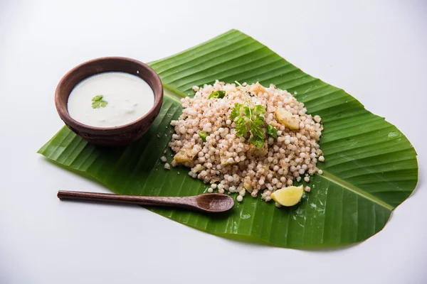 Sabudana Khichadi - Un plato auténtico de Maharashtra hecho con semillas de sagú servidas sobre hoja de coco con cuajada en un tazón de madera — Foto de Stock