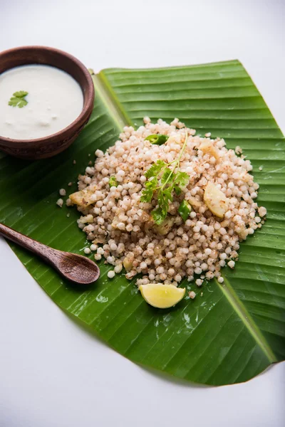 Sabudana Khichadi - An authentic dish from Maharashtra made with sago seeds served over coconut leaf with curd in a wooden bowl