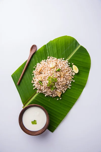 Sabudana Khichadi - An authentic dish from Maharashtra made with sago seeds served over coconut leaf with curd in a wooden bowl