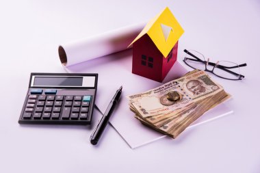 model ev, hesap makinesi, hint para notları, kalem ve gözlük kullanarak kredi veya kira kavramı ev satın alma