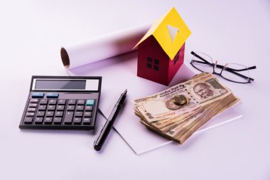 buying home on loan or rent concept using model house, calculator, indian currency notes, pen and spectacles clipart