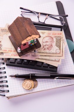 model ev, hesap makinesi, hint para notları, kalem ve gözlük kullanarak kredi veya kira kavramı ev satın alma