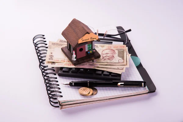 Compra de casa em empréstimo ou alugar conceito usando casa modelo, calculadora, notas de moeda indiana, caneta e óculos — Fotografia de Stock