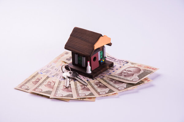 buying home on loan or rent concept using model house, calculator, indian currency notes, pen and spectacles