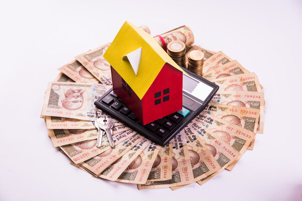 buying home on loan or rent concept using model house, calculator, indian currency notes, pen and spectacles