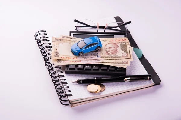 buying home and car concept, indian currency notes, model home, keys, toy car and calculator, isolated