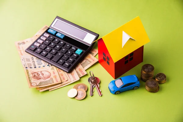 buying home and car concept, indian currency notes, model home, keys, toy car and calculator, isolated
