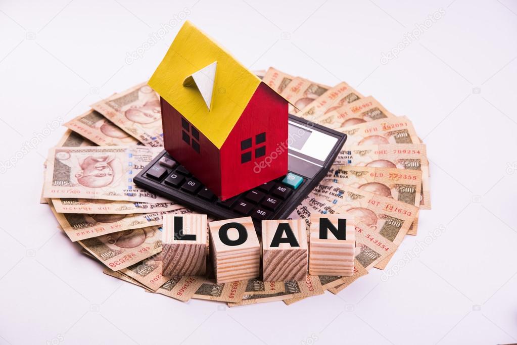 buying home on loan or rent concept using model house, calculator, indian currency notes, pen and spectacles