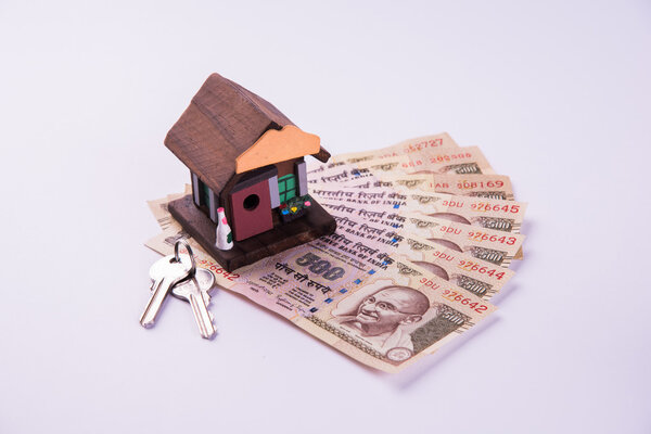 buying home on loan or rent concept using model house, calculator, indian currency notes, pen and spectacles