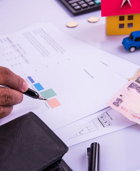 Indien homme ou comptable personne qui produit des déclarations de revenus indiennes formulaire ou document ITR montrant la monnaie indienne, modèle de maison, voiture jouet et calculatrice sur le dessus de table blanc, foyer sélectif — Photo