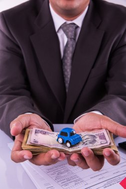 anahtar ile döviz notları ve oyuncak araba tutan Hintli işadamı, araba konsepti satın alma