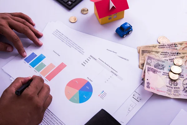 Hombre indio o contable persona que presenta formulario de declaración de impuestos indio o documento ITR que muestra moneda india, modelo de casa, coche de juguete y calculadora sobre mesa blanca, enfoque selectivo — Foto de Stock